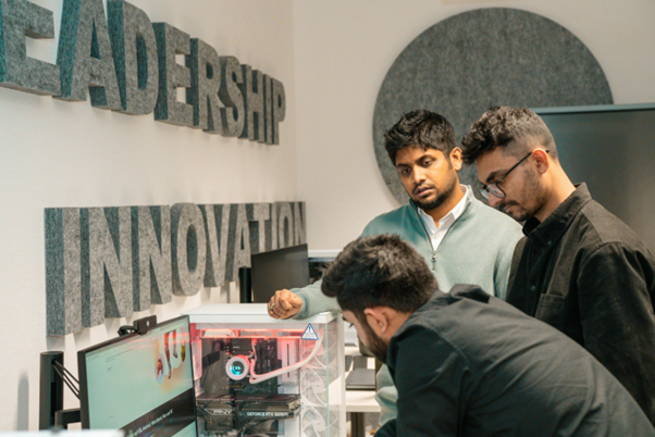 An instructor guiding trainees on an improvement technician apprenticeship through the process on a monitor.
