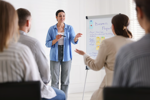 An instructor standing in front of a board coaching a group of improvement practitioner apprentices.